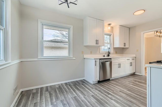 kitchen featuring stainless steel dishwasher, a chandelier, light wood-style flooring, and light countertops
