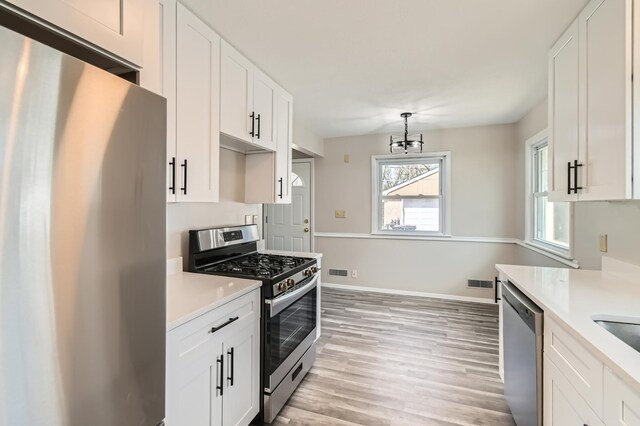 kitchen featuring stainless steel appliances, light countertops, light wood-type flooring, and white cabinets
