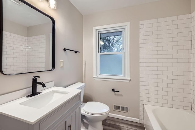 bathroom featuring wood finished floors, toilet, baseboards, vanity, and tub / shower combination
