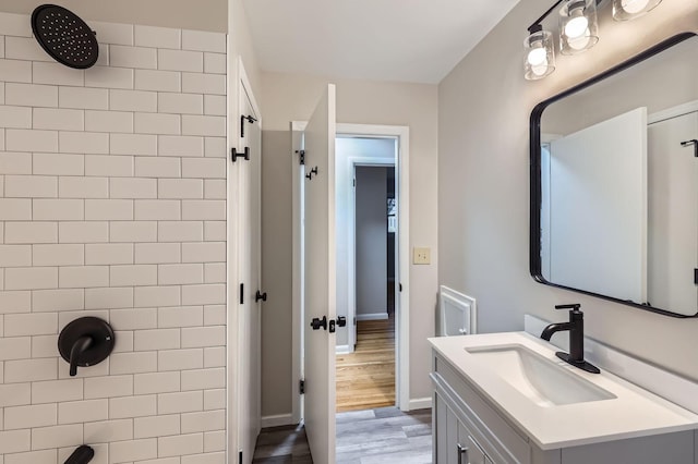 bathroom with a shower, vanity, wood finished floors, and baseboards