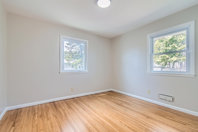 unfurnished room featuring plenty of natural light, light wood-style floors, and baseboards