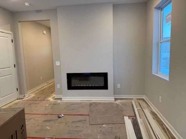 unfurnished living room featuring baseboards, a glass covered fireplace, and wood finished floors