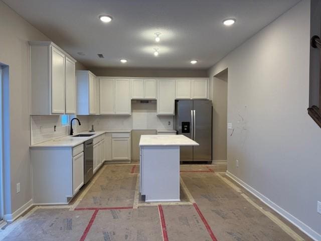 kitchen featuring a sink, stainless steel appliances, baseboards, white cabinetry, and a kitchen island