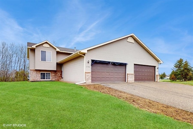 tri-level home with brick siding, a garage, a front lawn, and driveway