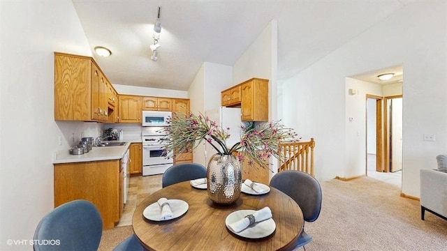 dining area featuring rail lighting, light carpet, and lofted ceiling