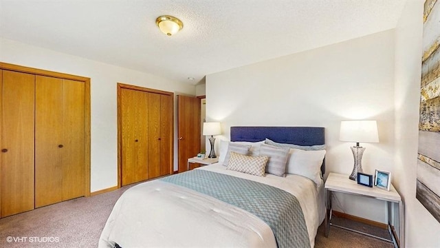 carpeted bedroom featuring baseboards and two closets