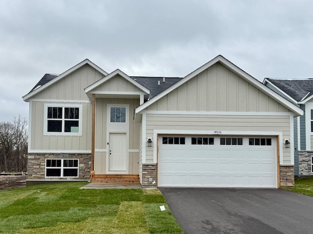 craftsman house featuring board and batten siding, a front yard, a garage, aphalt driveway, and stone siding