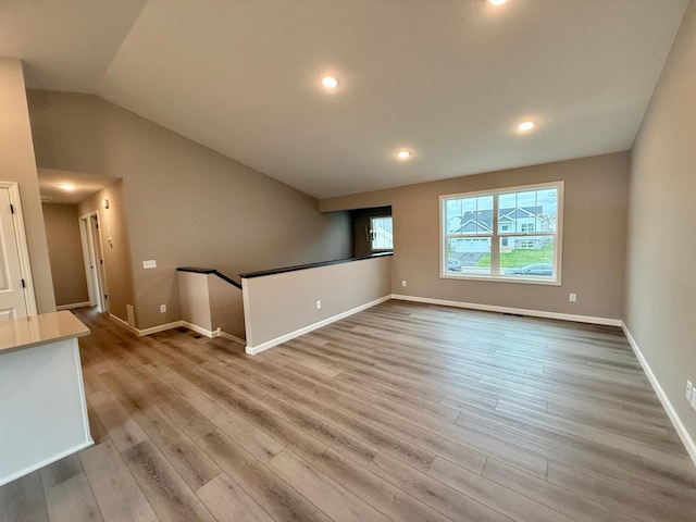 unfurnished living room with baseboards, lofted ceiling, and wood finished floors