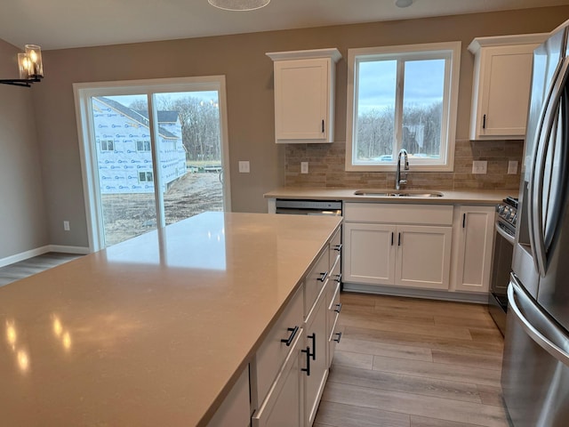kitchen with light countertops, tasteful backsplash, a sink, and light wood-style floors