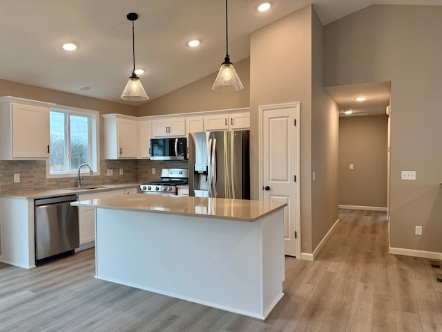 kitchen featuring appliances with stainless steel finishes, a sink, white cabinetry, backsplash, and vaulted ceiling