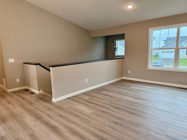 unfurnished room featuring baseboards, plenty of natural light, and wood finished floors