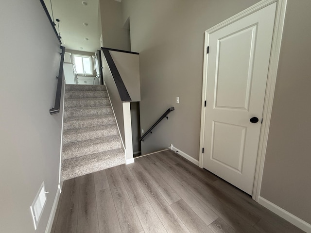 stairway featuring baseboards, visible vents, and wood finished floors