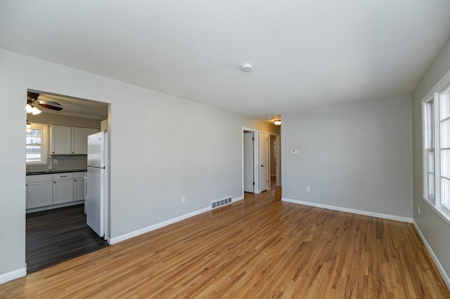 unfurnished living room featuring light wood-style flooring, baseboards, and healthy amount of natural light