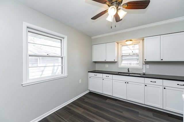 kitchen with a sink, dark countertops, dark wood-type flooring, white cabinetry, and a ceiling fan