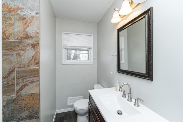 bathroom with toilet, vanity, baseboards, and wood finished floors