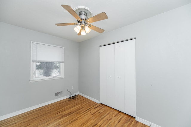 unfurnished bedroom with light wood-style floors, baseboards, a closet, and a ceiling fan