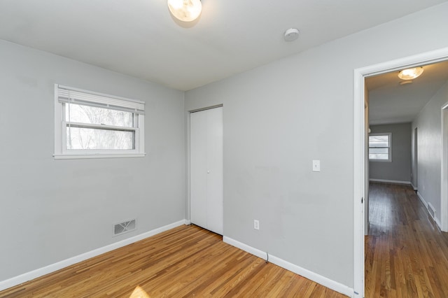 unfurnished bedroom with wood finished floors, baseboards, and a closet