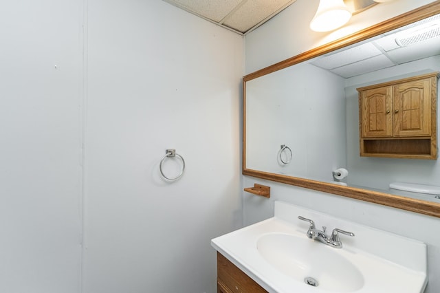 bathroom with a drop ceiling, vanity, and toilet