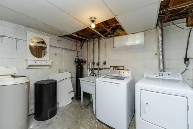 clothes washing area with washer and clothes dryer and concrete block wall