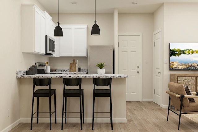 501 Redwood St N, Cambridge, MN 55008 - kitchen featuring a peninsula, light wood finished floors, stainless steel microwave, and a kitchen breakfast bar