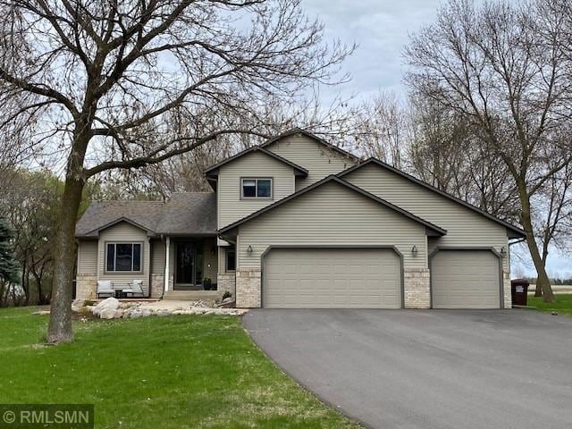 traditional home featuring brick siding, an attached garage, driveway, and a front yard