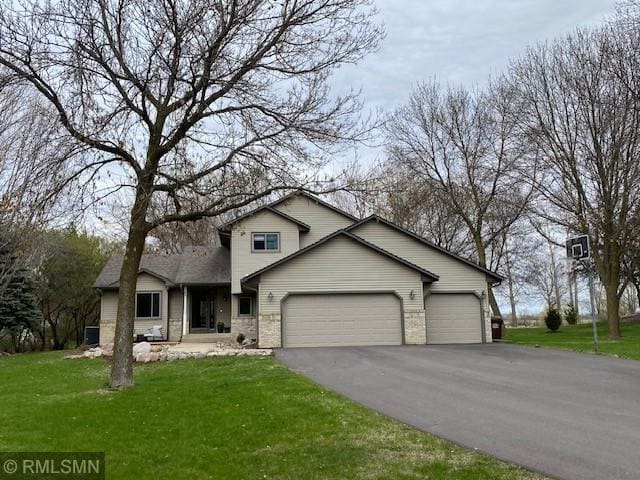 view of front of house featuring an attached garage, aphalt driveway, and a front yard