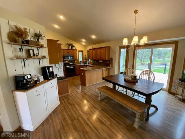 kitchen with a peninsula, stainless steel microwave, dark wood finished floors, and black range with gas stovetop
