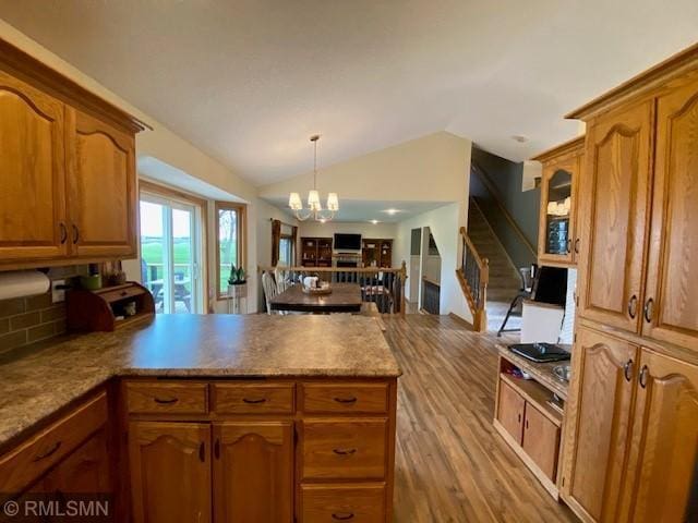 kitchen featuring a peninsula, open floor plan, brown cabinetry, and wood finished floors