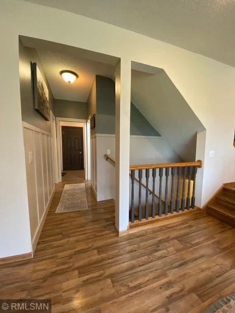 hallway with wood finished floors and an upstairs landing