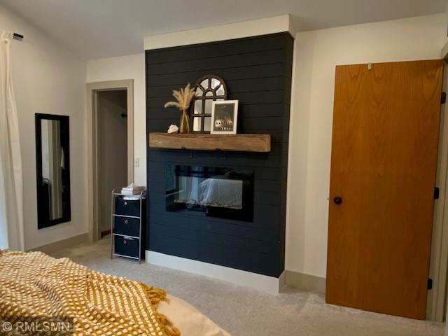 bedroom with baseboards, light colored carpet, and a fireplace