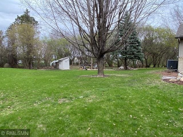 view of yard featuring central air condition unit, a shed, and an outbuilding