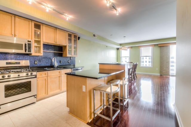 kitchen with appliances with stainless steel finishes, a sink, a breakfast bar area, rail lighting, and a center island