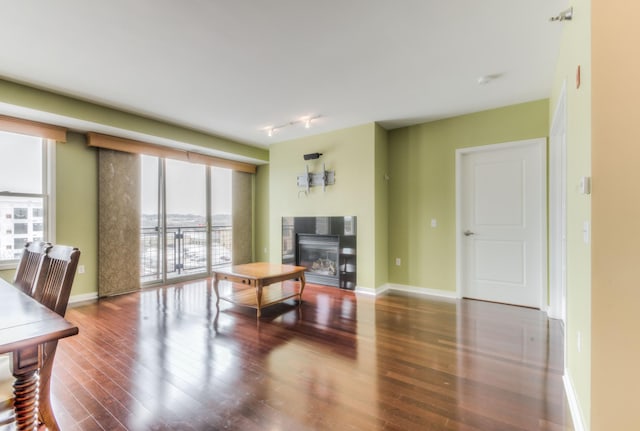 living room featuring baseboards, track lighting, wood finished floors, and a tile fireplace