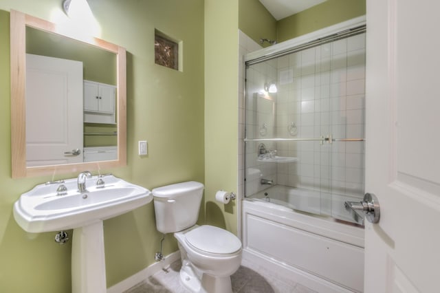 bathroom with toilet, baseboards, tile patterned flooring, and bath / shower combo with glass door