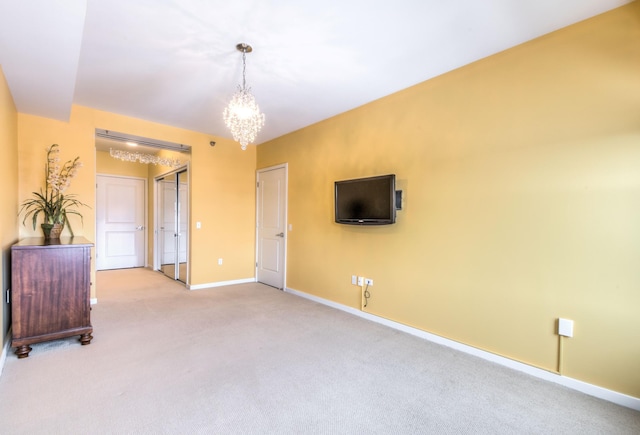 unfurnished living room featuring baseboards, a notable chandelier, and carpet