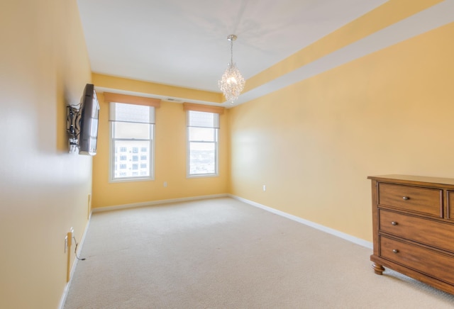 empty room with baseboards, light carpet, and a notable chandelier