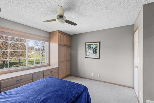 bedroom with light carpet, baseboards, a textured ceiling, and a ceiling fan