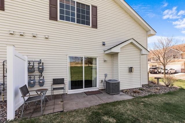 rear view of house with central AC unit, a patio area, and a yard