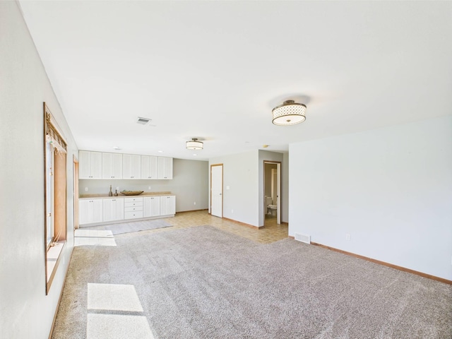 2200 Orchid Dr NE, Sauk Rapids, MN 56379 - unfurnished living room featuring baseboards, visible vents, and light colored carpet