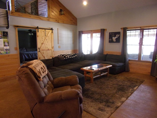 carpeted living room with a barn door and high vaulted ceiling