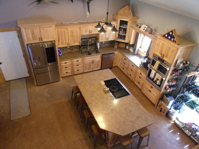 kitchen featuring ceiling fan, a kitchen bar, light brown cabinetry, appliances with stainless steel finishes, and glass insert cabinets