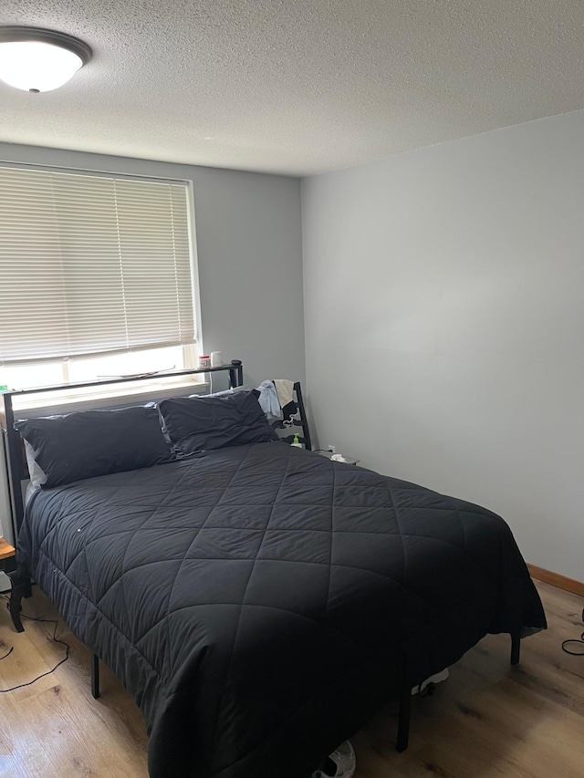 bedroom featuring wood finished floors and a textured ceiling