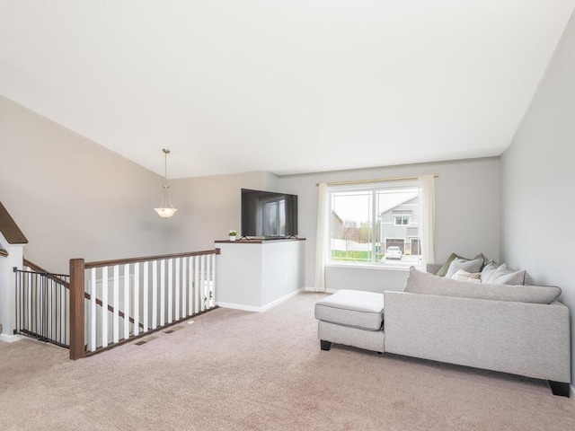 carpeted living area with baseboards and vaulted ceiling