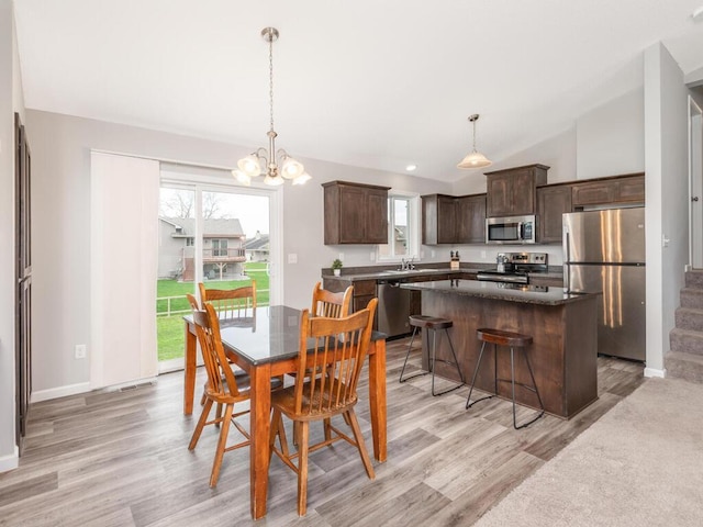 dining space featuring light wood finished floors, an inviting chandelier, baseboards, and lofted ceiling