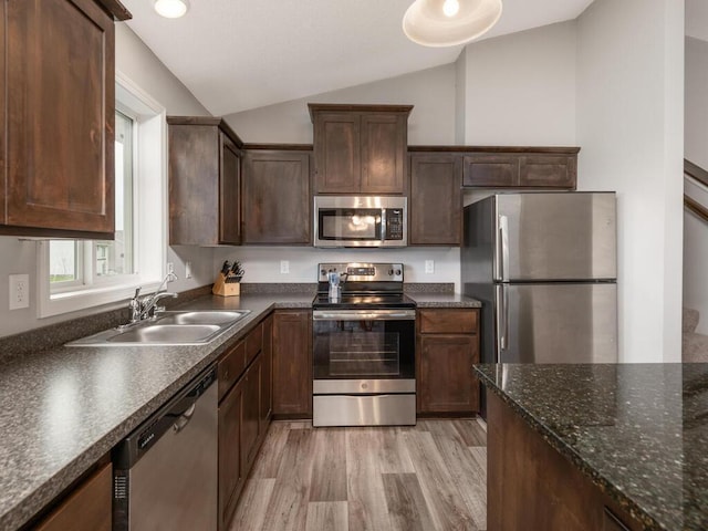 kitchen with dark brown cabinets, a sink, stainless steel appliances, light wood-type flooring, and vaulted ceiling