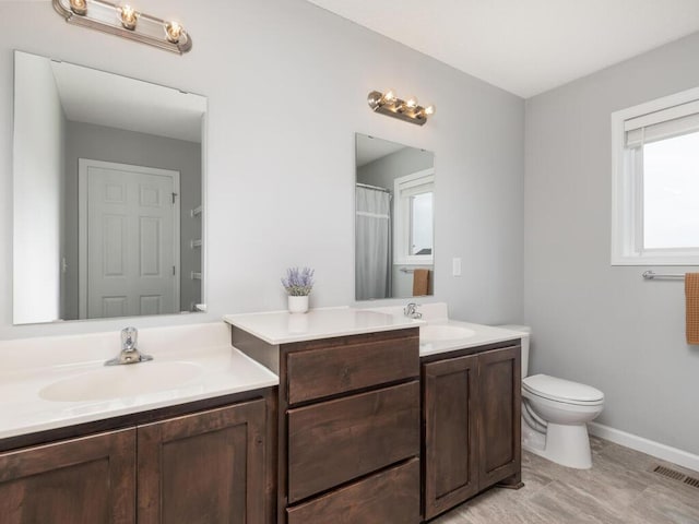 full bath featuring a sink, toilet, two vanities, and visible vents
