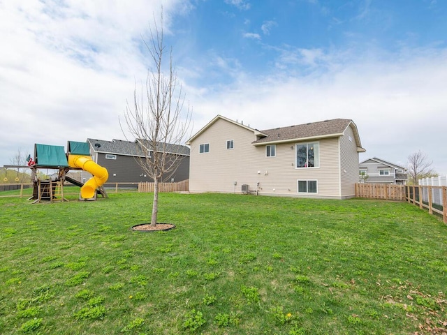 rear view of house featuring a fenced backyard, a playground, and a lawn