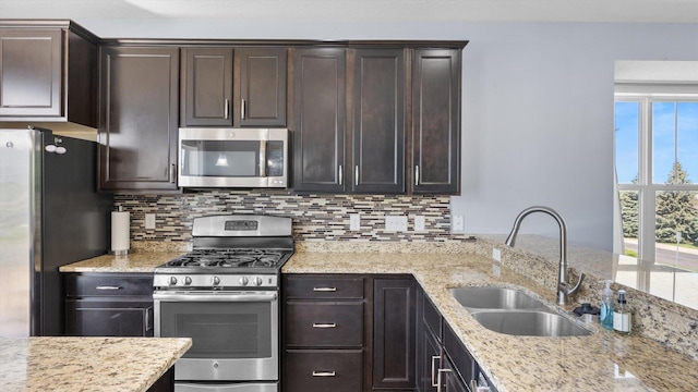 9645 Scott Ln N Unit 32, Brooklyn Park, MN 55443 - kitchen with stainless steel appliances, a sink, tasteful backsplash, dark brown cabinetry, and light stone counters