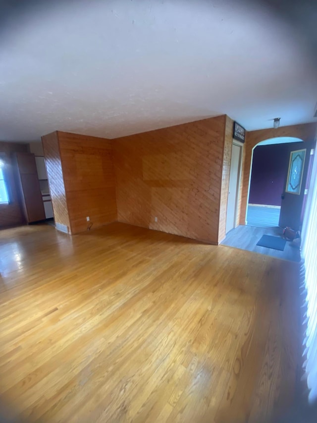 39 Erie St, Aurora, MN 55705 - spare room featuring wooden walls, arched walkways, and light wood-style floors