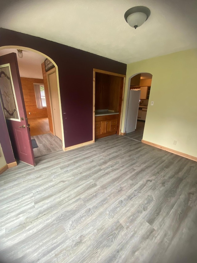 39 Erie St, Aurora, MN 55705 - unfurnished living room with arched walkways, baseboards, and wood finished floors